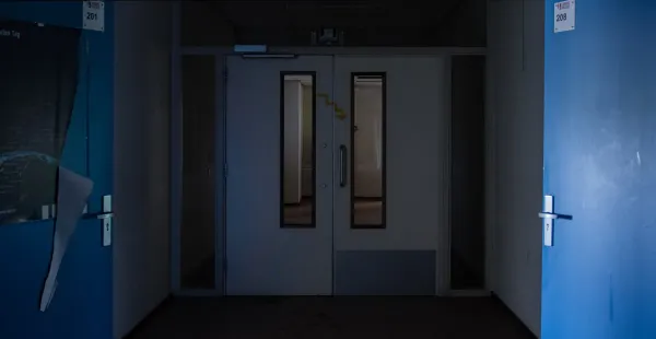 a dark hallway with a blue door and white walls