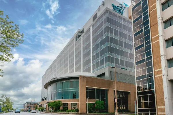 Modern glass building with curved entrance under sky.